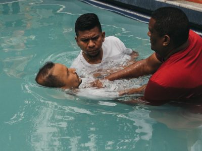 Três homens participam de uma cerimônia de batismo cristão em uma piscina