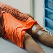 Close das pernas de uma mulher durante uma sessão de eletroterapia em ambiente hospitalar.